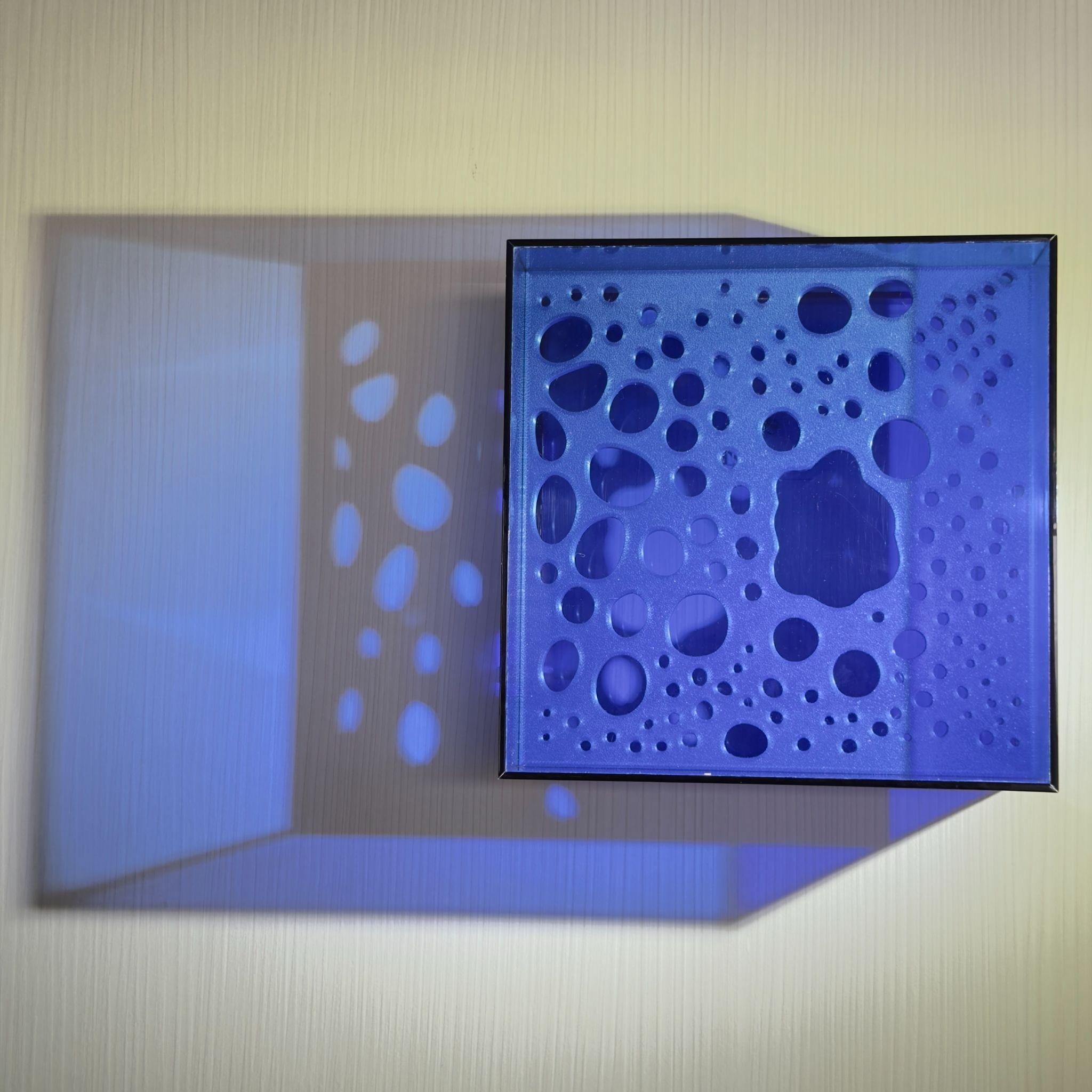 Caixa de luz azul de Cris Prado projetando formas orgânicas sobre a parede